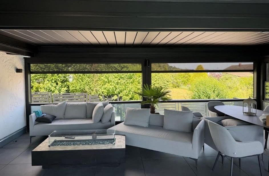 Loungemöbel und Esstisch unter dem geschlossenen Lamellendach, dahinter Zipscreens und Garten