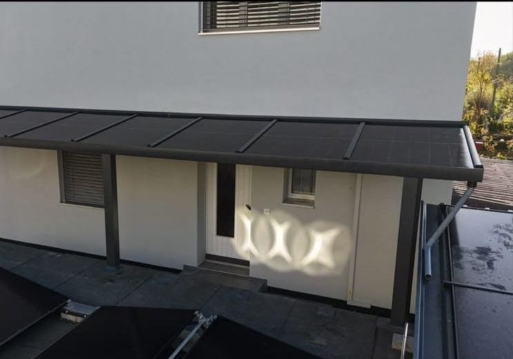 Das Solardach über dem Hauseingang, an der Wand das Lichtmuster zwischen den Zellen